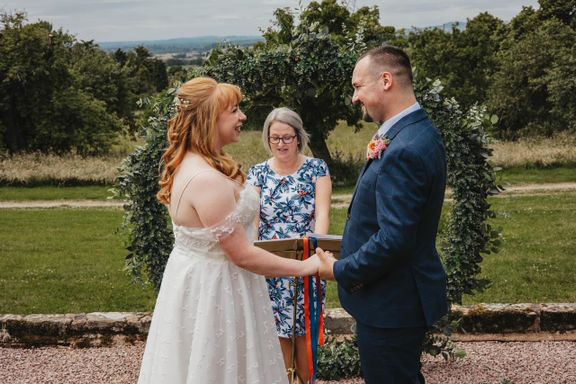 Katie and Mitch holding hands as Helen reads their promises to each other
